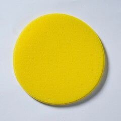 Round yellow sponge object isolated on square white background from top angle view.