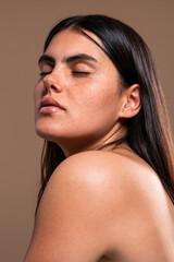 Beautiful young woman showing her tattoo and freckles in a studio portrait