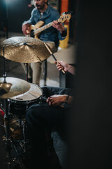 Musicians performing a rehearsal, focusing on a drummer playing and a bassist strumming in harmony. This captures artistic expression and preparation for a live music performance.