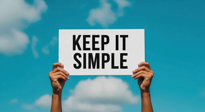 Hands Holding Sign with 'Keep It Simple' Message Against a Blue Sky Background