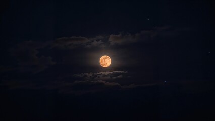 Full reddish moon on a cloudy summer evening, famously known as the Super strawberry moon.