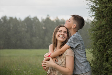 A happy and loving family in nature. A beautiful young mother with a smile on her face is standing...