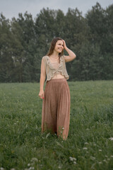 A beautiful young woman walks through a field, enjoying the warm summer rain.