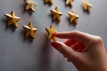 A hand tapping a golden star on a gray background