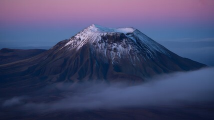 A snow-capped mountain peak emerges majestically through a sea of clouds, painted with the soft hues of dawn