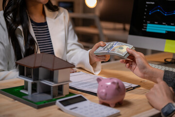 A woman is giving money to a man at a desk