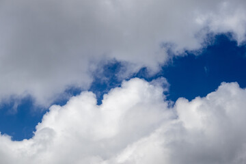 Bright blue sky partially obscured by towering white cumulus clouds, creating a vivid contrast of color and texture