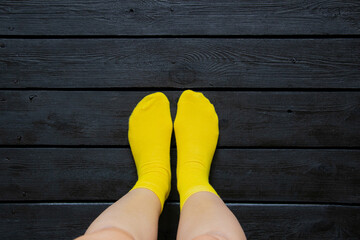 Female legs in bright yellow socks on dark wooden floor at home
