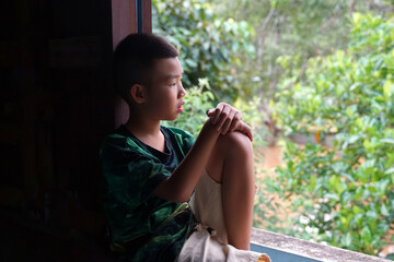 A boy sits alone on the windowsill, looking out at the flooded house.