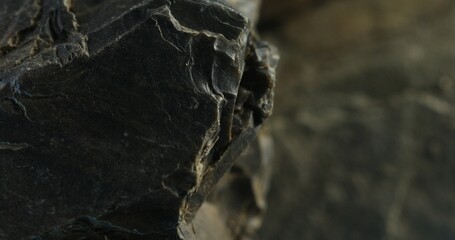 Close-up of dark fractured stone with curved edges and layered rock face