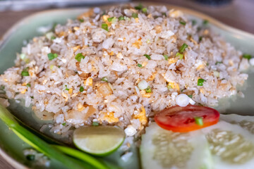 Fried rice with egg served on plate, with tomato, lime and lemon grass