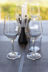 Two elegant empty wine glasses sit on a modern table setting, with soft natural light creating a refined atmosphere. The blurred background adds a tranquil and inviting ambiance.