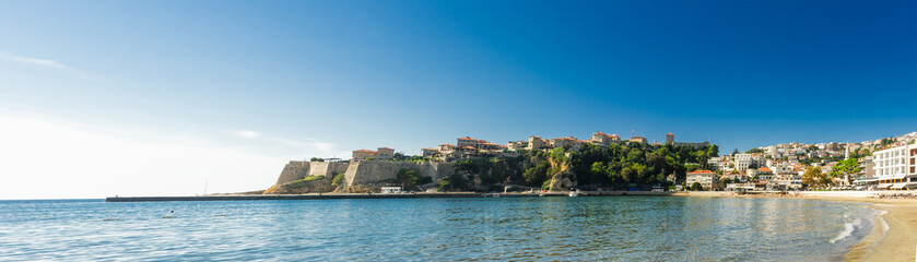 View of Ulcinj’s Old Town and sandy beach along the Adriatic coast, showcasing medieval fortress walls, hillside houses, and a bright summer seascape.