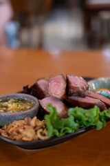 Grilled beef tongue served on plate with pickled egg yolk and sauce