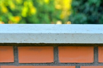 View of the brick base. Brick wall with white finished top with polished white capstone. Brick backdrop. Brick background with polished top with headstone. Building and construction concept.