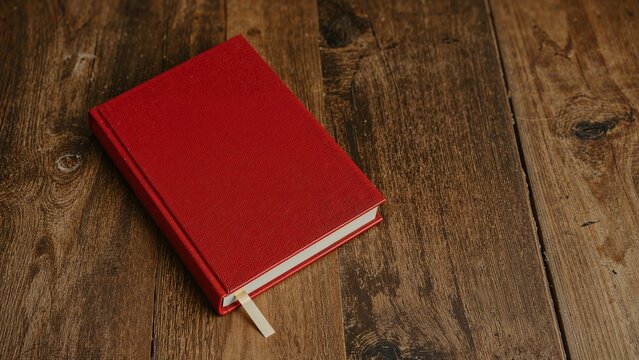 Vintage-style image of a red hardcover book on a textured wooden tabletop