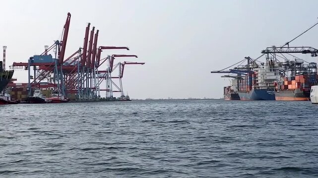 Container ships loading and discharging by shore crane in International Port of Tanjung Priok. Logistics and transportation of shipping, steve doring and lift on lift off at container yard. Jetty view
