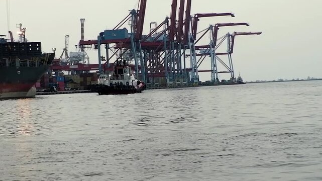 Container ships loading and discharging by shore crane in International Port of Tanjung Priok. Logistics and transportation of shipping, steve doring and lift on lift off at container yard. Jetty view