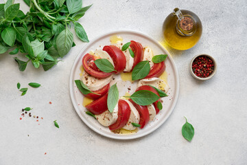 Fresh Caprese Salad with Mozzarella Cheese, Ripe Tomatoes, and Green Basil Leaves on White Background. Healthy Mediterranean Food Concept