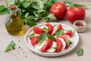 Fresh Caprese Salad with Mozzarella Cheese, Ripe Tomatoes, and Green Basil Leaves on White Background. Healthy Mediterranean Food Concept
