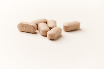 Lion’s mane mushrooms tablets that have beneficial effects on the body, especially the brain, heart, and intestines. Bright paper background. Soft focus. Close up. Copy space.	