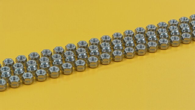 Chain of hex-shaped nuts on a vivid yellow surface