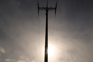 Obraz premium A tall power pole with a sun shining on it