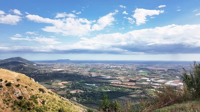 Aerial time lapse over Agro Pontino starting from the mountains behind Norma with wider vistas of Sermoneta the Circeo the Pontine Islands and the city of Latina with farmland sky and clouds in motion