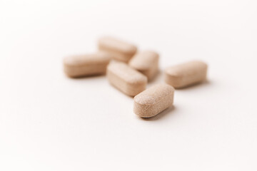 Lion’s mane mushrooms tablets that have beneficial effects on the body, especially the brain, heart, and intestines. Bright paper background. Soft focus. Close up. Copy space.	