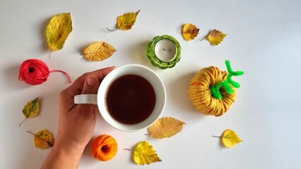  autumn frame background with a cup of tea held in a hand and decorations made of pumpkins, autumn...