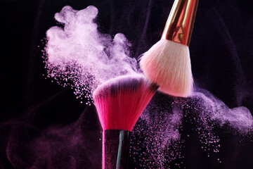 Makeup brushes with colorful eye shadows on black background, closeup