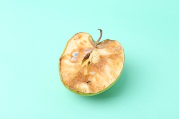Half of spoiled apple on turquoise background, top view