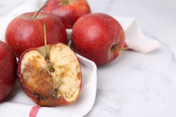 Spoiled apple and good ones on white table, closeup