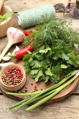 Different fresh herbs, spices and thread on wooden table, closeup