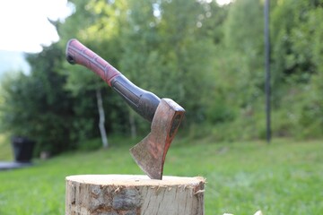 Metal axe and wooden log outdoors, closeup