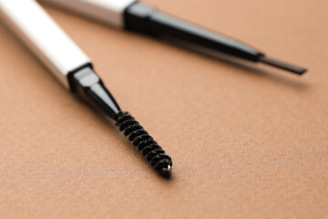 Automatic eyebrow pencils on brown background, macro view