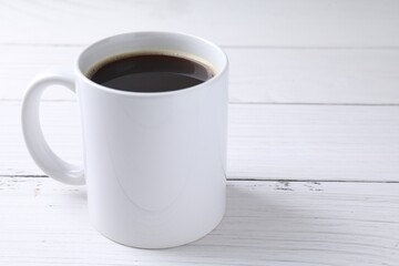 Tasty coffee in cup on white wooden table, closeup. Space for text