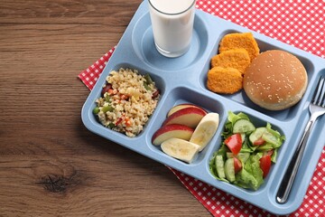 Plastic tray with tasty food, milk and fork on wooden table, above view. School lunch