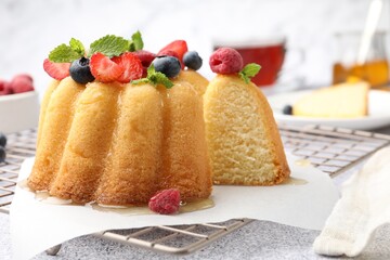 Tasty Bundt cake with berries, honey and mint on light grey table, closeup