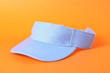 One light blue visor cap on orange background, closeup. Mockup for design