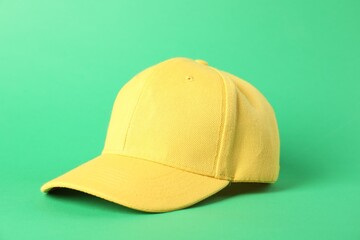 One yellow baseball cap on green background, closeup. Mockup for design