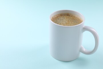 Aromatic coffee in cup on light turquoise background, closeup. Space for text