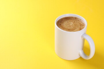 Aromatic coffee in cup on yellow background, closeup. Space for text