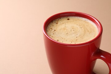 Aromatic coffee in cup on beige background, closeup. Space for text