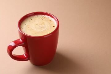 Aromatic coffee in cup on beige background, closeup. Space for text