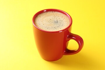 Aromatic coffee in cup on yellow background, closeup