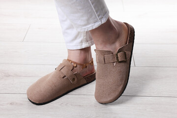 Woman in stylish beige slippers on light wooden floor, closeup