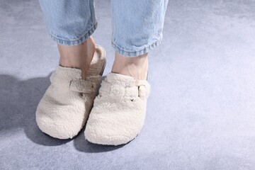 Woman in stylish white slippers on grey textured floor, closeup