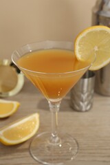 Tasty lemon cocktail in glass and bartender equipment on wooden table, closeup