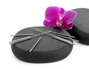 Acupuncture needles, orchid flower and spa stones isolated on white
